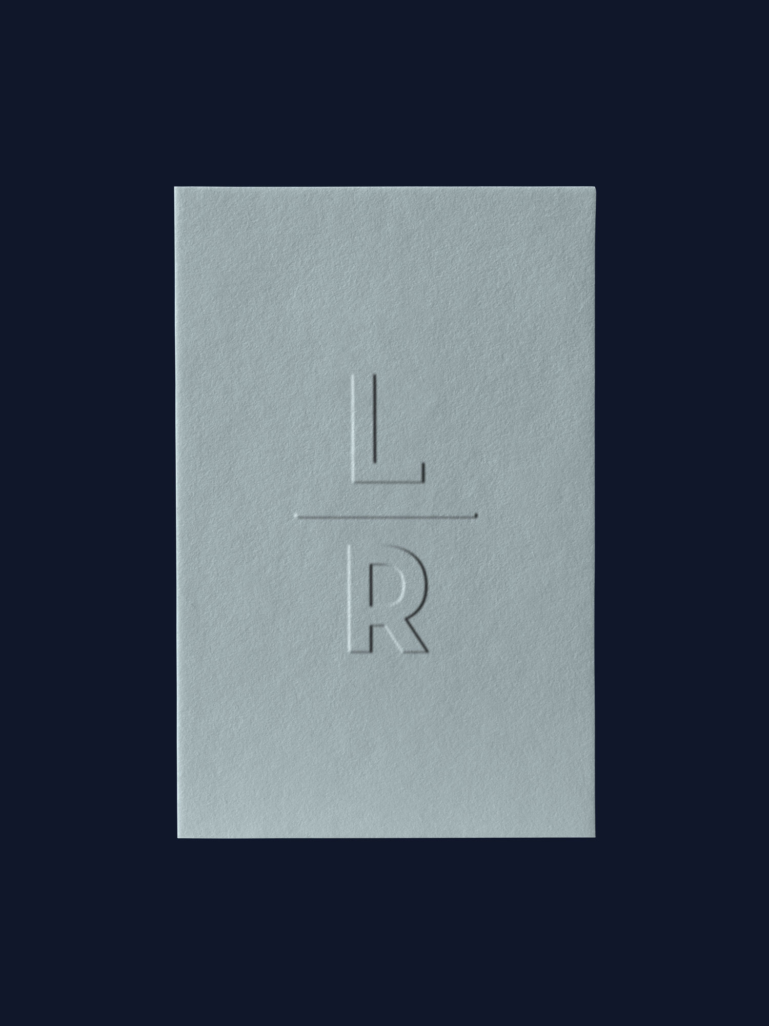 Embossed LuRu Home LR monogram logo on soft blue gray textured business card, minimalist design over navy background