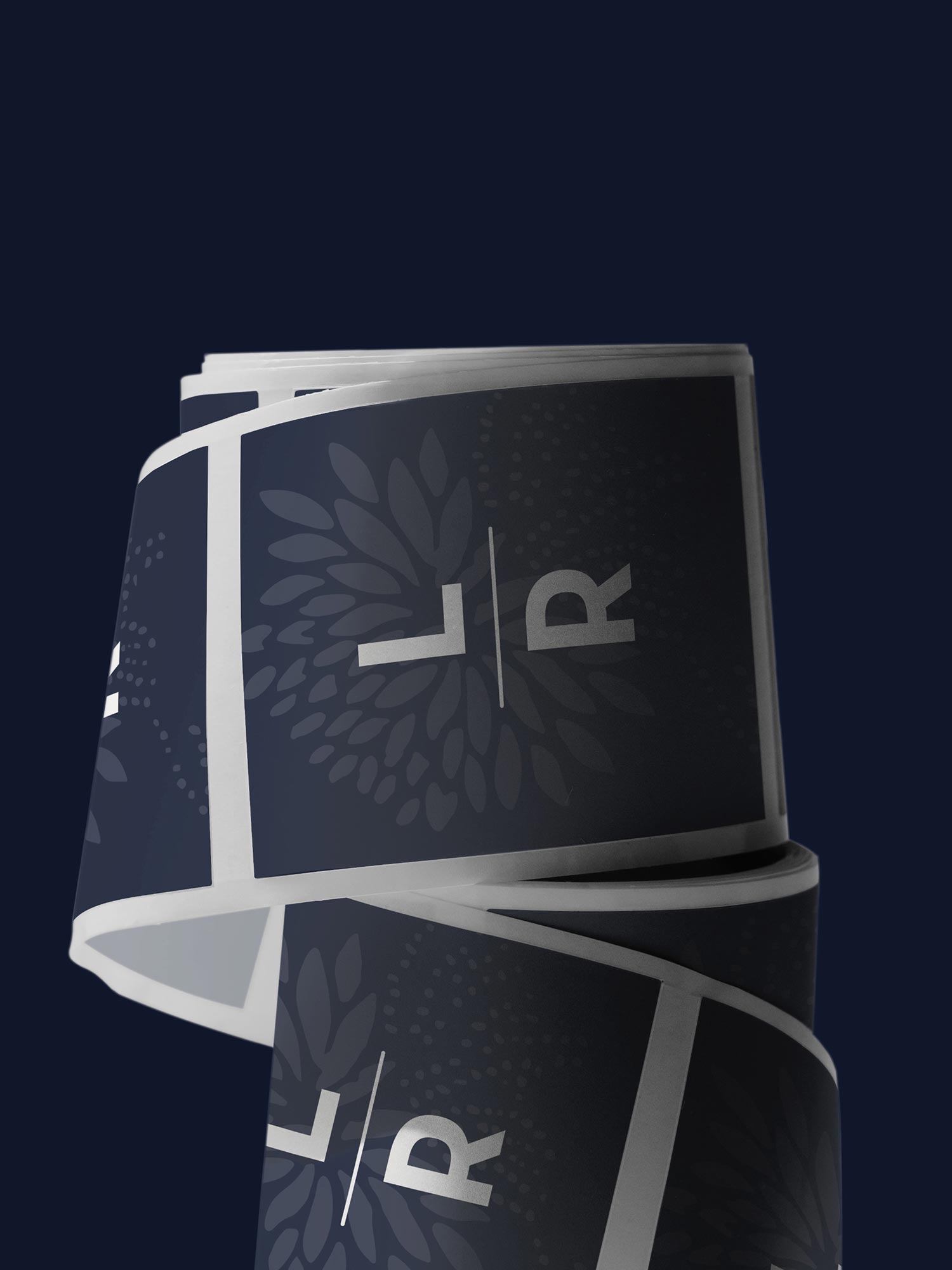 Roll of navy packaging labels featuring LuRu Home LR monogram logo and subtle floral pattern in matte finish
